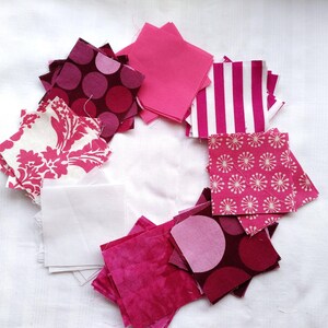 May include: A collection of pink and white fabric squares with various patterns, including polka dots, floral designs, and stripes. The squares are arranged in a circle on a white background.