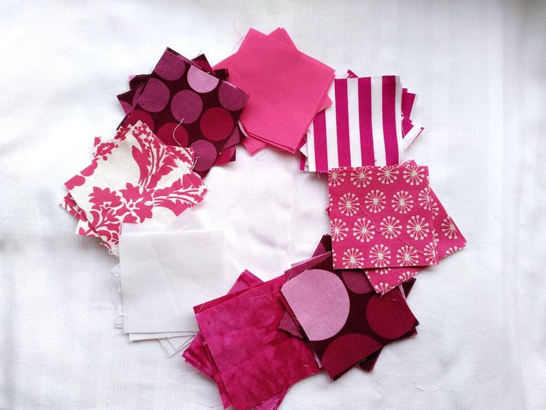 May include: A collection of pink and white fabric squares with various patterns, including polka dots, floral designs, and stripes. The squares are arranged in a circle on a white background.