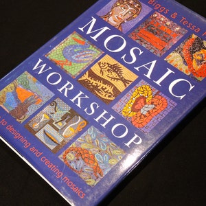May include: A blue book titled "Mosaic Workshop: a guide to designing and creating mosaics" by Biggs & Tessa Hunckin. The cover features colourful mosaic designs of a bird, fish, heart, and other patterns.