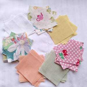 May include: Assortment of fabric squares in various colors and patterns, including floral, polka dot, and solid colors. The squares are arranged in a circle on a white surface.