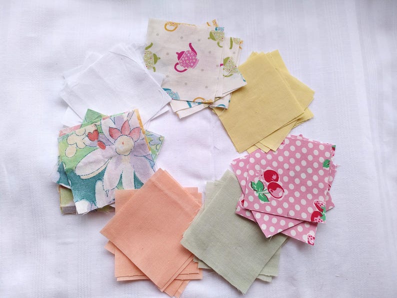 May include: Assortment of fabric squares in various colors and patterns, including floral, polka dot, and solid colors. The squares are arranged in a circle on a white surface.