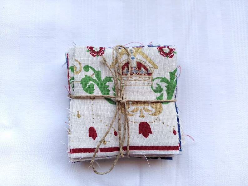 May include: A stack of fabric squares with a white background and a gold, green, and red floral pattern. The fabric is tied together with twine.
