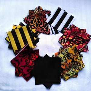 May include: A collection of fabric squares in various patterns and colors, including black and white stripes, red and black floral designs, and yellow and black stripes. The squares are arranged in a circle on a white background.