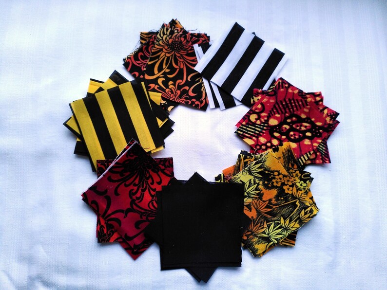May include: A collection of fabric squares in various patterns and colors, including black and white stripes, red and black floral designs, and yellow and black stripes. The squares are arranged in a circle on a white background.
