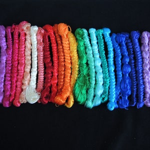 May include: A collection of colorful embroidery floss spools in various shades of pink, red, orange, yellow, green, blue, and purple.