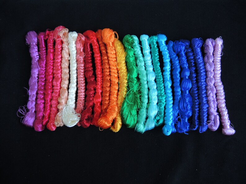 May include: A collection of colorful embroidery floss spools in various shades of pink, red, orange, yellow, green, blue, and purple.