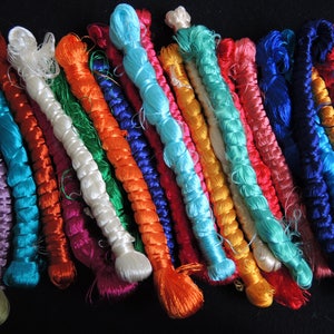 Puede incluir: Una colecci&oacute;n de hilos trenzados de colores en varios tonos de azul, verde, rojo, naranja, morado y blanco. Los hilos est&aacute;n dispuestos en una fila y todos tienen aproximadamente la misma longitud.