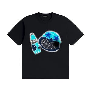 May include: A black short-sleeve t-shirt featuring a graphic print of a stylised blue character with a wide, grid-patterned mouth and star-shaped eyes, holding a blue bottle. The word "smile" is printed on the bottle and the inner neck label.