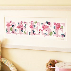 Puede incluir: Una impresión enmarcada rosa y blanca con el nombre "REESE" escrito en letras grandes. Cada letra está decorada con flamencos rosas, hojas de palmera verdes y flores rosas. La impresión está enmarcada en un marco de madera blanco.