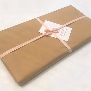May include: A brown paper package wrapped with a pink ribbon and tied with a bow. A white card with text is attached to the ribbon.