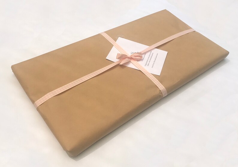 May include: A brown paper package wrapped with a pink ribbon and tied with a bow. A white card with text is attached to the ribbon.