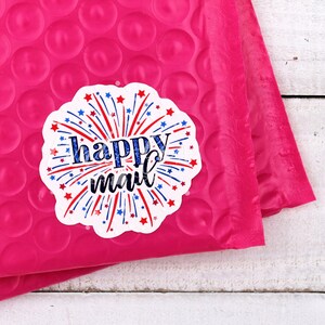 Puede incluir: Un sobre de burbujas rosa con una pegatina blanca que dice "happy mail" con fuegos artificiales rojo, blanco y azul.