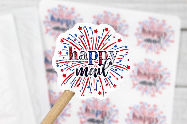 Puede incluir: Una pegatina blanca con un dise&ntilde;o de fuegos artificiales rojo, blanco y azul. El texto "happy mail" est&aacute; escrito en letras cursivas negras.