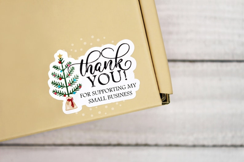 May include: A white sticker with a green Christmas tree with red and blue ornaments, a brown gift bag, and the text 'thank YOU! FOR SUPPORTING MY SMALL BUSINESS'.