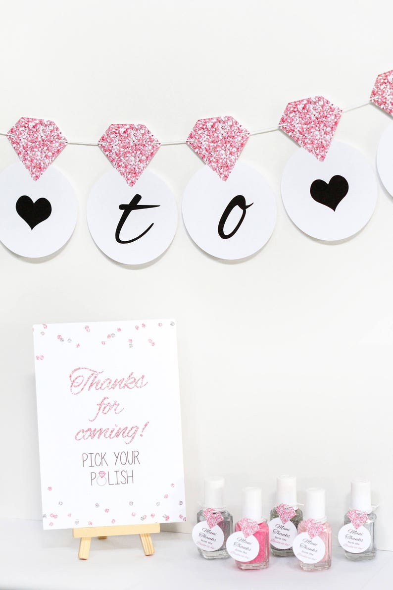 May include: A pink and white sign with the text "Thanks for coming! Pick your polish" and a pink diamond graphic.  There are six small bottles of nail polish with pink and white labels that say "Mom Thanks from the Bride".