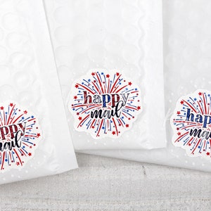 Puede incluir: Tres sobres blancos para correo con pegatinas de "happy mail" rojas, blancas y azules con un dise&ntilde;o de fuegos artificiales.