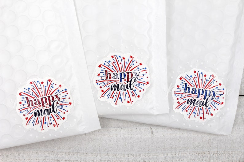 Puede incluir: Tres sobres blancos para correo con pegatinas de "happy mail" rojas, blancas y azules con un dise&ntilde;o de fuegos artificiales.
