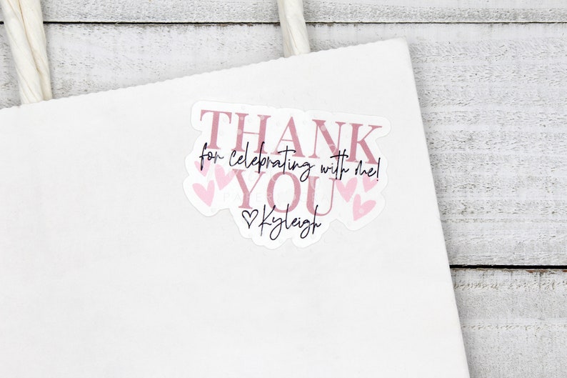 May include: Pink thank you sticker with the text "Thank you for celebrating with me!" and "Kaleigh" with pink hearts around the text.