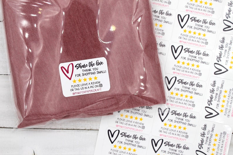 May include: White sticker with black text that reads "Share the love, thank you for shopping small!" with a black heart and five gold stars. The text also includes "Please leave a review or tag us in a pic on @pinkfoxpapercraft".