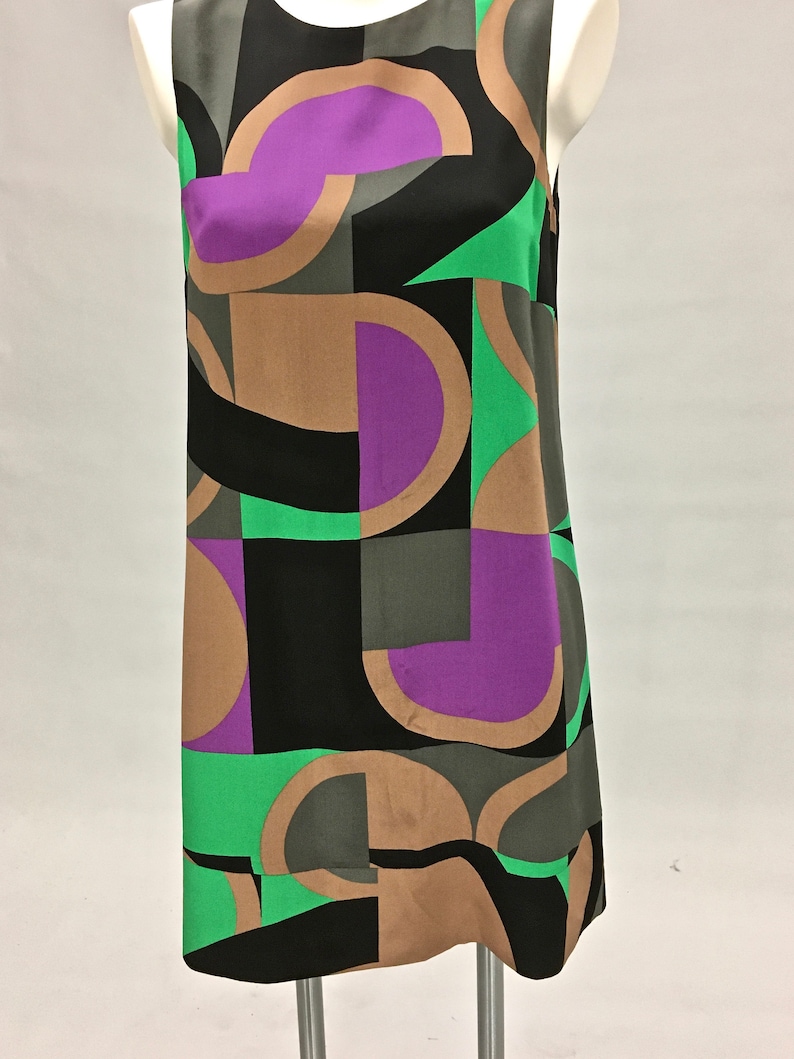 May include: A sleeveless dress with a geometric pattern in shades of brown, green, purple, and black.
