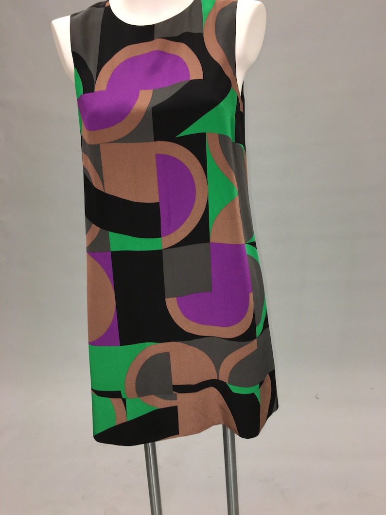 May include: A sleeveless dress with a geometric pattern in shades of brown, black, green, and purple.