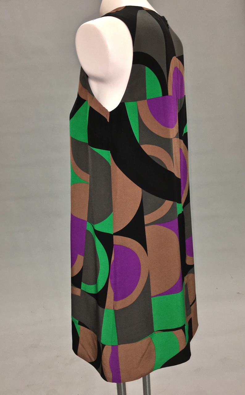May include: A sleeveless dress with a geometric pattern in shades of black, brown, green, and purple.