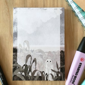 May include: A white ghost with two black eyes stands in a field of tall, dark green grass. The background is a hazy, gray landscape with a hint of blue in the distance.