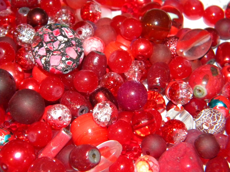 Peut inclure: Un grand assortiment de perles rouges de formes, tailles et textures vari&eacute;es. Les perles sont en verre, en plastique et en d'autres mat&eacute;riaux.