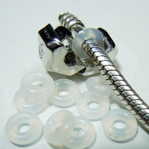 May include: A silver snake chain bracelet with a silver clasp and clear silicone spacer beads.