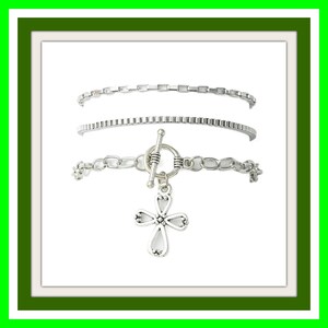May include: A set of three silver-toned bracelets. The top bracelet features a flat rectangular link chain, the middle is a textured box chain, and the bottom is a cable chain with a toggle clasp and a decorative four-petaled cross charm.