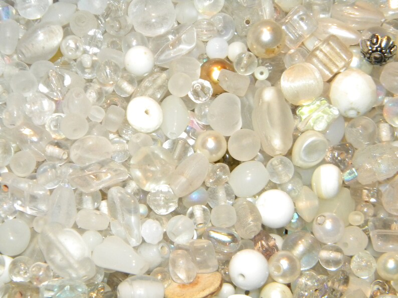 Peut inclure: Un grand assortiment de perles de verre blanches et transparentes, certaines avec des finitions iris&eacute;es. Les perles sont de formes et de tailles vari&eacute;es, notamment rondes, ovales et en forme de larme.
