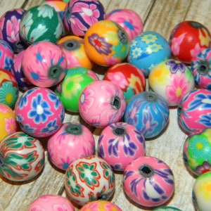 May include: A collection of colourful round beads with floral patterns. The beads are made of polymer clay and have a glossy finish.