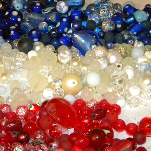 Peut inclure: Une collection de perles de verre color&eacute;es dans des tons de bleu, blanc et rouge. Les perles sont dispos&eacute;es de mani&egrave;re al&eacute;atoire et sont de diff&eacute;rentes tailles et formes.
