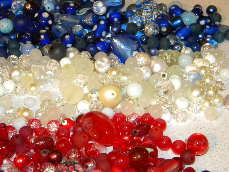 Peut inclure: Une collection de perles de verre color&eacute;es dans des tons de bleu, blanc et rouge. Les perles sont dispos&eacute;es de mani&egrave;re al&eacute;atoire et sont de diff&eacute;rentes tailles et formes.