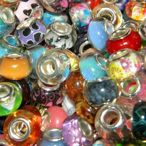 May include: A collection of colorful glass beads with silver-toned metal cores. The beads feature various designs, including floral patterns, animal prints, and solid colors like red, blue, and orange. These decorative beads are suitable for jewelry making.