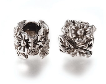 Könnte beinhalten: Zwei silberne Blumencharms aus Metall, einer mit einem Blumendesign und der andere mit einem Blumendesign und einer hohlen Mitte.