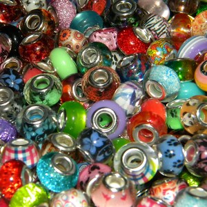 May include: A collection of colorful charm beads with various designs and textures. The beads are made of glass and feature patterns like floral, glitter, and stripes. Each bead has a silver-toned core, creating a vibrant and eye-catching assortment.