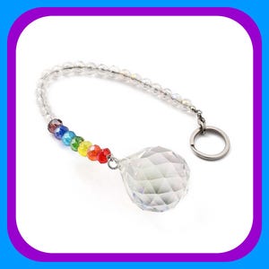 May include: A clear crystal ball with a rainbow of beads hanging from it. The crystal ball is attached to a silver chain with a key ring.
