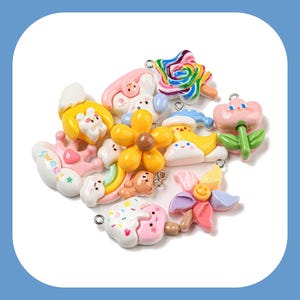 May include: A collection of colorful, whimsical charms featuring various designs, including a flower, a cloud, a rainbow, a bear, a cupcake, and a star. The charms are made of ceramic and have a glossy finish.