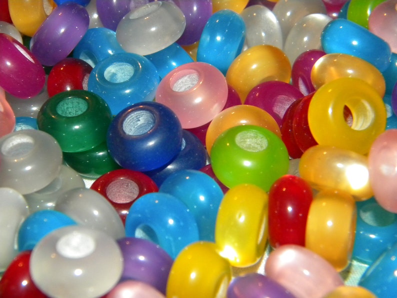 May include: A collection of round, translucent beads in a variety of vibrant colors including blue, green, yellow, red, purple, pink, and white. Each bead features a smooth, polished finish and a central hole, creating a colorful assortment.
