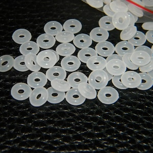 May include: A large quantity of white plastic spacer beads. The beads are round with a hole in the centre.