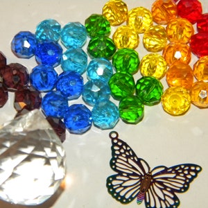 May include: A rainbow assortment of faceted glass beads, a clear crystal prism, and a metal butterfly charm. The beads are arranged in a rainbow pattern, with red, orange, yellow, green, blue, and purple beads.