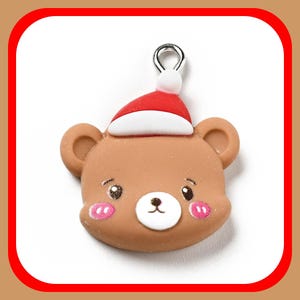 May include: A brown bear charm with a red and white Santa hat. The bear has a cute cartoon face with pink cheeks and a silver loop for hanging.