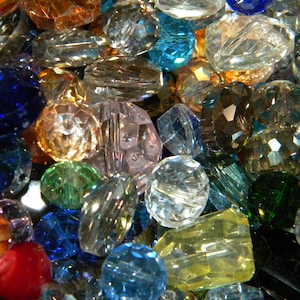 May include: A collection of colorful glass beads in various shapes and sizes. The beads are clear, blue, green, red, and orange. They are perfect for jewelry making or crafting.