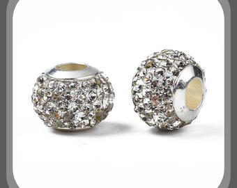 May include: Two silver-toned, round beads encrusted with sparkling, clear crystals. The beads have a central hole and a silver-colored metal cap. The crystals reflect light, creating a dazzling effect. These beads are suitable for jewelry making.
