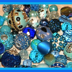 May include: Assortment of blue, teal, and green glass beads, some with rhinestones, for jewelry making.