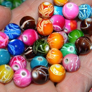 May include: A collection of colorful round beads with white swirl designs. The beads are made of plastic and have a glossy finish.