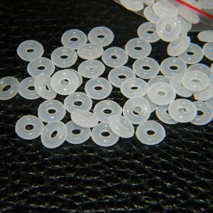 May include: A large quantity of white plastic spacer beads. The beads are round with a hole in the centre.