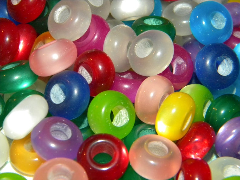 May include: A collection of round, smooth, translucent beads in a variety of vibrant colors including red, blue, green, yellow, pink, and white. Each bead features a central hole, creating a uniform shape across the assortment of colorful pieces.