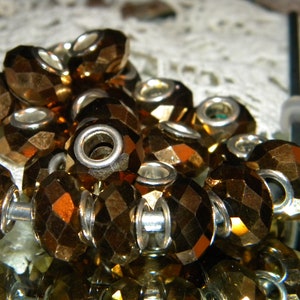 May include: A close-up of a pile of gold-toned glass beads. The beads are faceted and have a hole in the center. They are arranged in a random pattern.